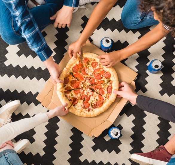 cropped image of teens taking pizza pieces